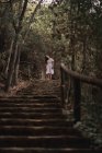 Dal basso di misteriosa donna calma in abito bianco in piedi sulle scale nel parco autunnale calmo — Foto stock