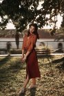 Femme en chemisier vintage romantique et jupe debout dans la pose gracieuse croisée sur l'herbe tenant livre dans les mains — Photo de stock