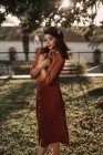 Жінка в романтичній старовинній блузці і спідниці, що стоїть в схрещеній витонченій позі на траві тримає книгу в руках — стокове фото