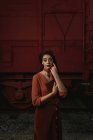 Donna totalmente indossando vestiti in terracotta in stile vintage in piedi vicino treno auto in terracotta e tenendo aperto libro in mano — Foto stock