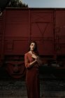Mulher vestindo roupas de terracota em estilo vintage em pé perto de trem de carro de terracota e segurando livro aberto — Fotografia de Stock