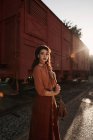 Жінка в одязі теракотового одягу в старовинному стилі стоїть біля поїзда з теракотовим автомобілем і тримає відкриту книгу — стокове фото