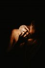 High angle of naked woman covering chest with hand and holding luminous ball in dark — Stock Photo