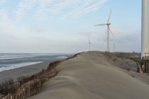 Lonely tourist on sandy hill near windmills — Stock Photo