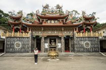 Voyageuse en tenue décontractée prenant des photos devant la caméra avec le magnifique temple taoïste Dai Quan Tang à Taiwan — Photo de stock