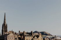 Старая темная башня, расположенная среди старых домов на фоне пасмурного неба на городской улице в Эдинбурге, Шотландия, Великобритания — стоковое фото