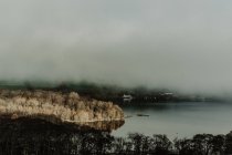 Von oben des nebligen Herbstwaldes mit Sonnenstrahlen in der Nähe des Sees mit Nebel — Stockfoto