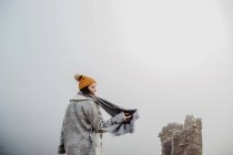 Side view of lady in warm clothes walking in foggy park on cloudy daytime — Stock Photo