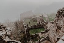 Ancien château en pierre détruit avec brouillard avec murs et escaliers avec tour pendant la journée nuageuse — Photo de stock