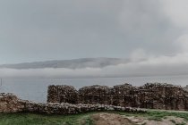 Vista desde las paredes de edificios arruinados de montañas y colinas brumosas con niebla en el día nublado - foto de stock