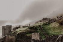 Зруйнований старий кам'яний замок з туманом зі стінами та сходами з вежею в похмурий день — стокове фото