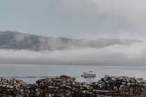 Каменная стена разрушенного старого замка против облачного неба с видом на туманные горы — стоковое фото
