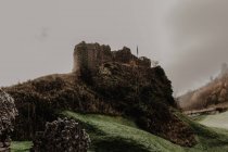 Зруйнований старий кам'яний замок з туманом зі стінами та сходами з вежею в похмурий день — стокове фото