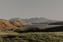 Montanhas com rochas e lago contra céu azul claro com raios de paisagem de luz solar da natureza selvagem no outono — Fotografia de Stock