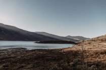 Горы со скалами и озеро на фоне ясного голубого неба с лучами солнечного света в ландшафте дикой природы осенью — стоковое фото