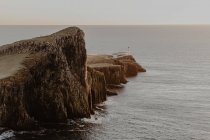Scogliere costiere e faro di Neist Point vicino al mare contro un cielo azzurro e sereno durante il giorno soleggiato nell'Isola di Skye, Scozia — Foto stock