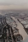 Dall'alto vista aerea della città densamente popolata con strade e case nascoste dietro nuvole bianche — Foto stock