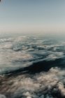 Dall'alto di nuvole bianche in cielo sopra paesaggio scuro — Foto stock