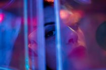 Close-up de mulher olhando na câmera entre luzes de néon coloridas na rua da cidade — Fotografia de Stock