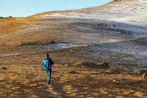 Viajante com mochila andando ao longo do vale seco na montanha — Fotografia de Stock
