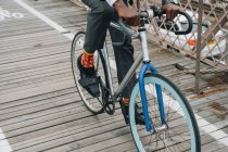 Обрезанный образ хорошо одетый бизнесмен велосипедист в езда на велосипеде по деревянной дороге среди красного металла структуры с в Нью-Йорке — стоковое фото