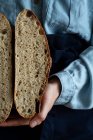 Mano di donna anonima che tiene fette di pane di pasta madre fatto in casa . — Foto stock