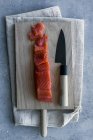 Сверху аппетитный свежий нарезанный лосось на столе с деревянной доской и ножом на льняном полотенце — стоковое фото