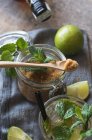 Limas frescas aéreas e folhas de hortelã-pimenta colocadas em guardanapo e mesa perto de rum e açúcar mascavo para preparação de mojito — Fotografia de Stock