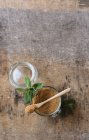 Sucre brun frais dans un bocal et feuilles de menthe poivrée placées sur une table en bois — Photo de stock