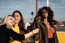 Cheerful young diverse female friends celebrating meeting in city — Stock Photo