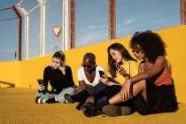 Unbekümmerte junge multirassische Freundinnen mit Smartphone im Stadion — Stockfoto