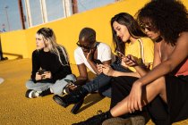 Беззаботные молодые многорасовые подруги используют смартфон на стадионе — стоковое фото