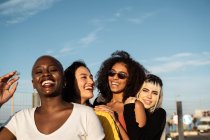 Confident young multiethnic female friends enjoying pastime in street — Stock Photo