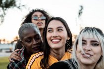 Різноманітна група усміхнених жінок, що обіймаються разом на газоні — стокове фото
