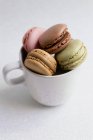 Vista de ângulo alto da xícara de macaroons coloridos macios no fundo branco — Fotografia de Stock