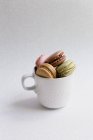 High angle view of cup of tender colorful macaroons on white background — Stock Photo