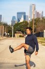 Hispanic male runner in active wear stretching and warming up before practice in downtown Dallas, USA — Stock Photo