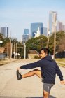 Ispanico corridore maschile in abbigliamento attivo che si estende e si riscalda prima dell'allenamento nel centro di Dallas, USA — Foto stock
