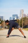 Un coureur hispanique en tenue active s'étire et se réchauffe avant la pratique dans le centre-ville de Dallas, USA — Photo de stock