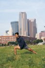 Fit sportsman in active wear making lunge in green park in downtown of Dallas, Texas, USA — Stock Photo