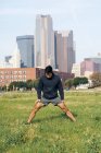 Ajuste deportista en desgaste activo que se extiende en el parque verde en el centro de Dallas, Texas, EE.UU. - foto de stock