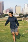 Sportsman ajuste no desgaste ativo esticando no parque verde no centro de Dallas, Texas, EUA — Fotografia de Stock