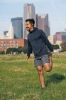 Молодий іспаномовний спортсмен у активному одязі, розтягнутий у зеленому парку в Далласі (штат Техас, Уса). — стокове фото