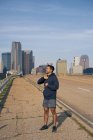 Young Hispanic male athlete with closed eyes standing on side of road in downtown Dallas, Texas — Stock Photo