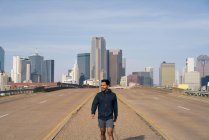 Jovem atleta masculino hispânico andando na berma da estrada no centro de Dallas, Texas — Fotografia de Stock