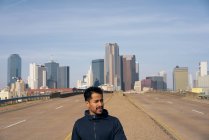 Jovem atleta masculino hispânico andando na berma da estrada no centro de Dallas, Texas — Fotografia de Stock