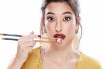 Senhora com maquiagem moderna degustação de alimentos com pauzinhos — Fotografia de Stock
