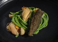 Carne exquisita con verduras de ajo servidas en un amplio plato negro - foto de stock