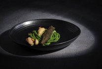 Carne requintada com legumes de alho servido em prato preto largo — Fotografia de Stock
