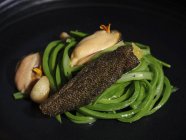 Carne requintada com legumes de alho servido em prato preto largo — Fotografia de Stock